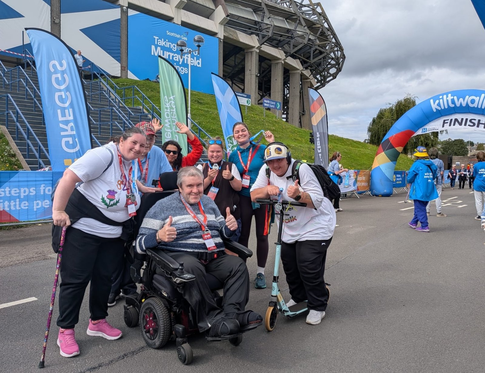 members Susan, George, Keoki, Weronika and Ambassador Natalie and Coordintor Mairi at the finish line of the Kiltwalk. Everyone is smiling with their medals!