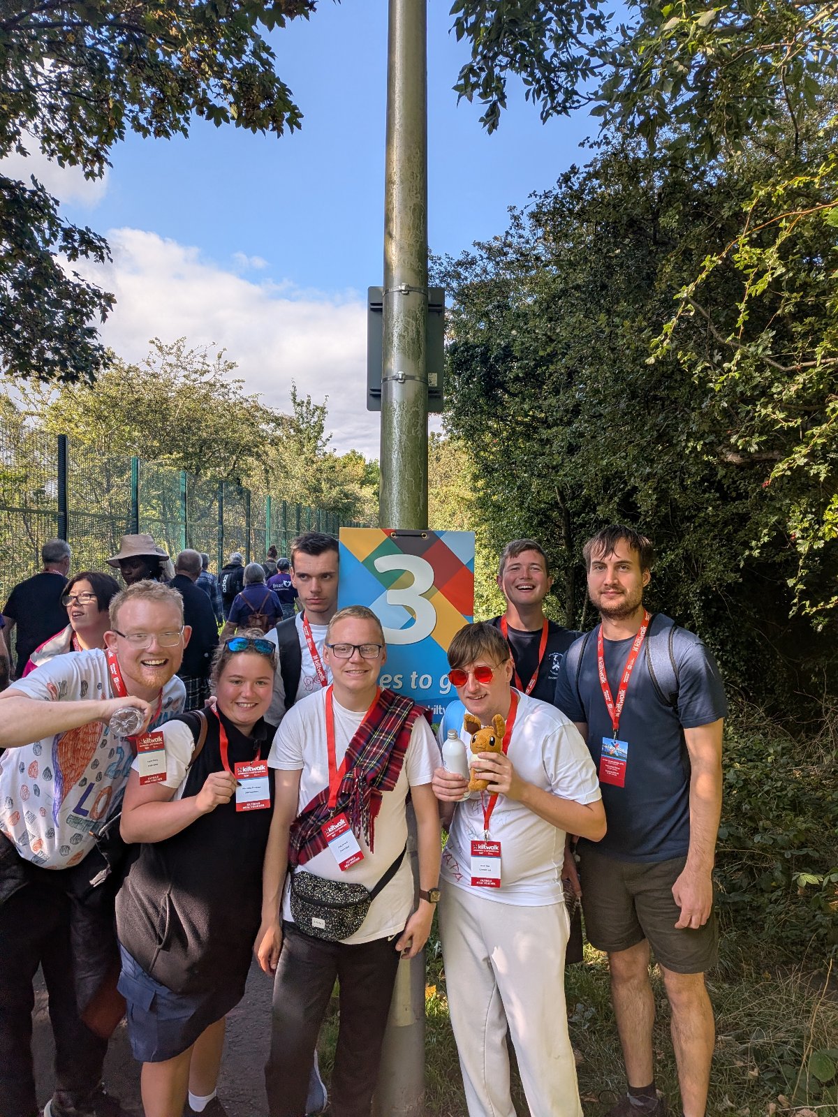 6 get2gether members posing for a picture at the 3 mile marker of the 2026 Kiltwalk.